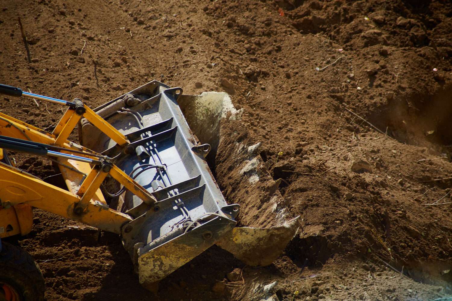 Bulldozer bucket digging soil close-up, bulldozer bucket working with soil, bulldozer excavation and earthworks, bulldozer bucket clearing construction site