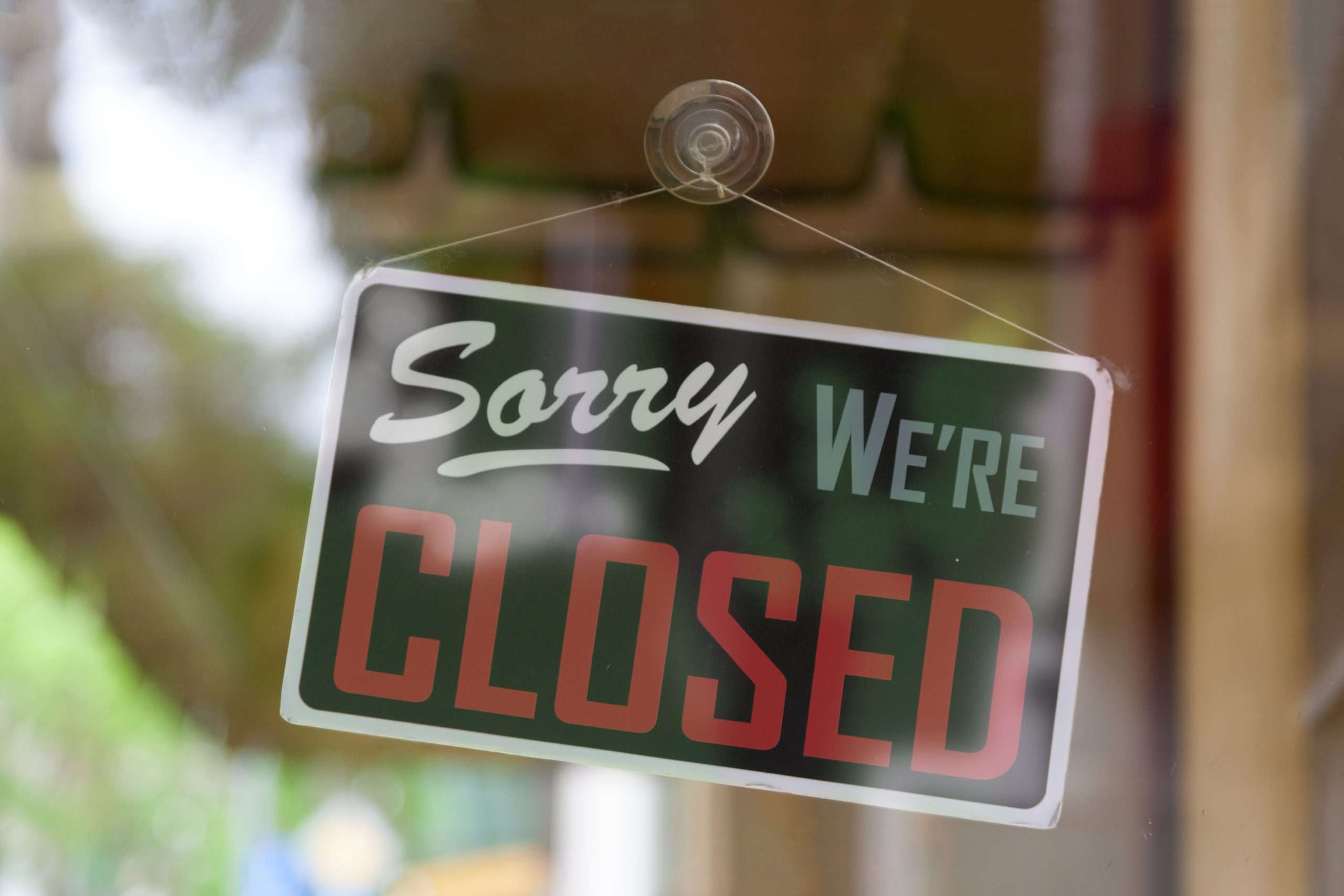 Close-up on an closed sign in the window of a shop saying "Sorry, we're closed".