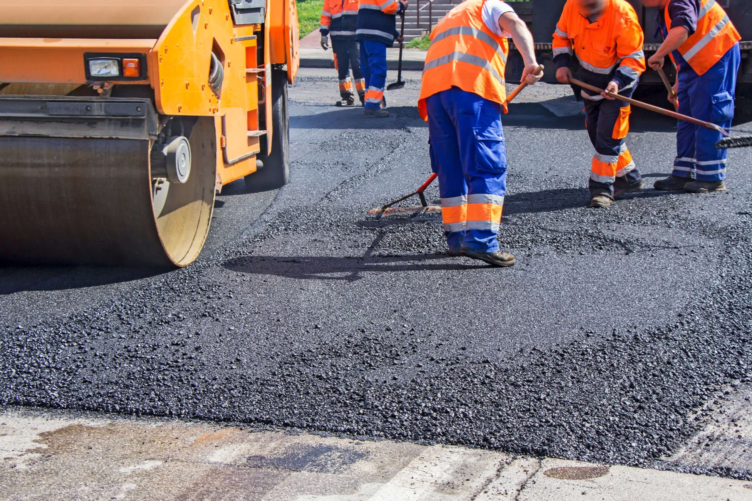 Roller and workers on asphalting and repair of city streets