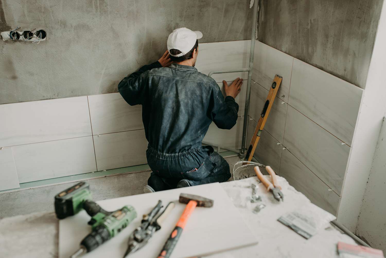 Worker repairman puts large ceramic tiles on the walls in the room