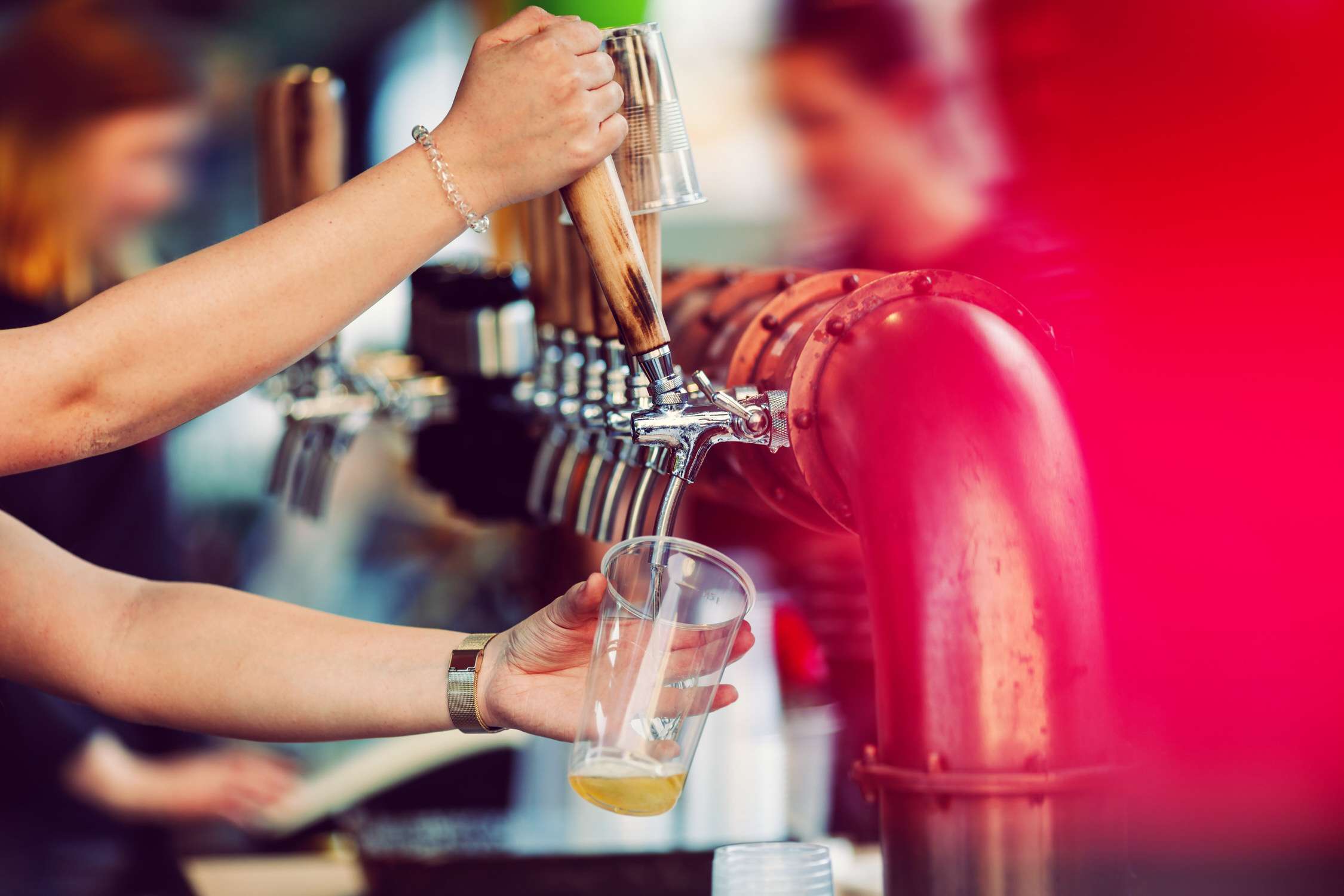 Beer tapping with traditional taps into a plastic cup and colorful  blurred background