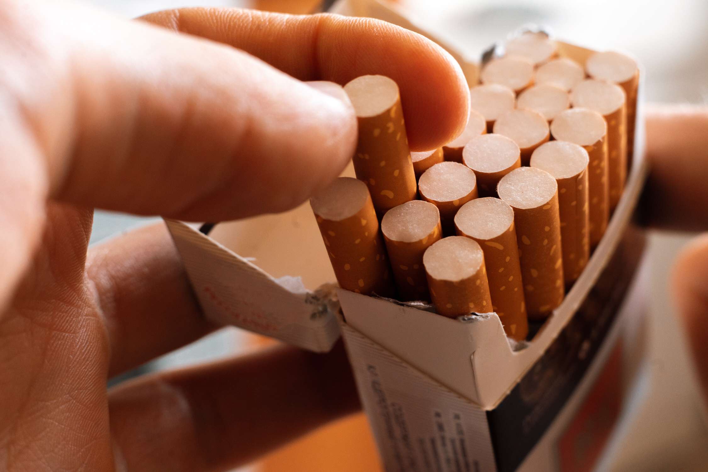 close up of person's hand pick a cigarette from the carton pack box